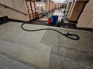Pohled na žulové schodiště čištěné pomocí mobilního čisticího zařízení, ukazující kontrast mezi čištěnými a nečištěnými oblastmi.