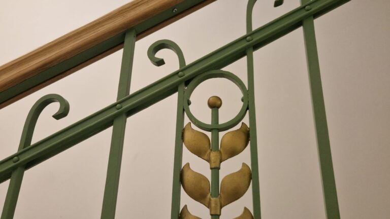 Zelené zábradlí s dekorativními prvky.